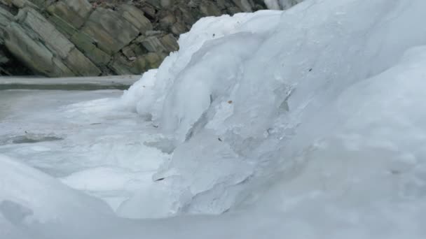 Wintertime, fast flowing stream under frozen river — Stock Video