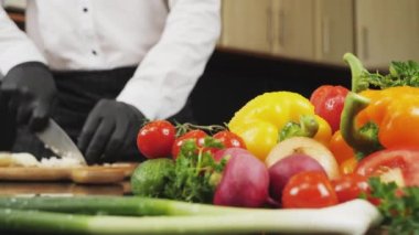 Şef ağaç kesme tahtasıyla sebze doğruyor.