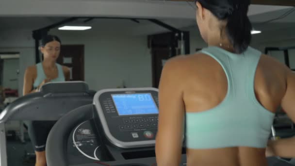 Young athletic woman runs on a treadmill in the gym. — Video