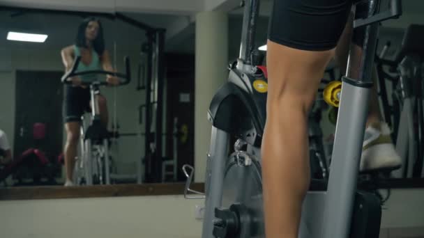 헬스 장에서 운동용 자전거를 타는 젊은 여자 — 비디오