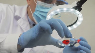 Mikroskop önünde çalışan bir tıp çalışanı.