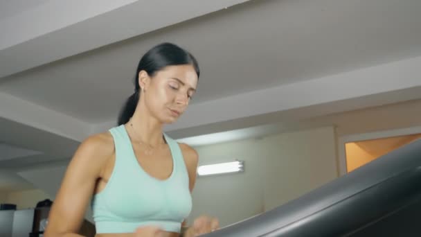 Chica joven corriendo en la cinta en la sala de fitness. — Vídeos de Stock