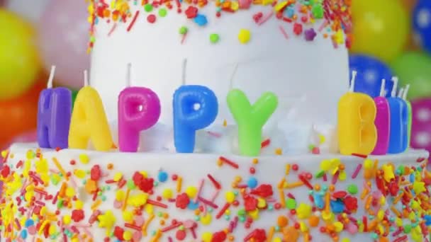 Tarta de cumpleaños con velas con globos de colores sobre fondo borroso — Vídeos de Stock