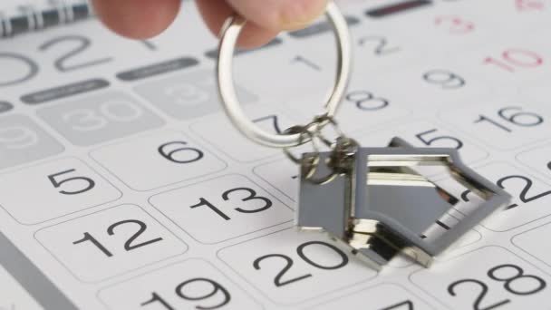 Sleutel met huisvormige sleutelhanger en wandkalender — Stockvideo