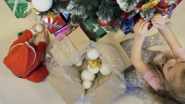 Hermana y su hermano pequeño decoran el árbol de Navidad — Vídeos de Stock