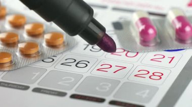 Vurgulanmış tarihler ve reçeteli haplarla dolu bir takvimin yakın görüntüsü, ilaç takvimlerini etkin bir şekilde yöneten bir sistemi gösterir.