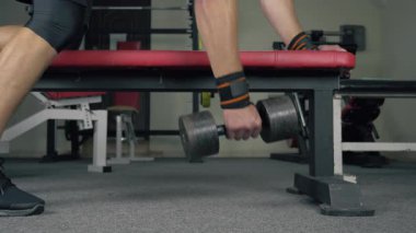 Atletizm sporcusu halterlerle antreman tezgahında egzersiz yapıyor.