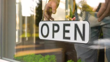 Vitrindeki bir pencereye yazıtlı pano kapatılmış. Bir insan iş gününün sonunda asılma işaretini çevirir..