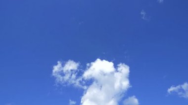 Beyaz kabarık bulutlarla dolu berrak mavi bir gökyüzü yavaşça hareket ediyor. Atmosfer sakin ve bir huzur ve rahatlama hissi uyandırıyor..