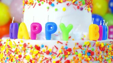 Canlı bir doğum günü pastası rengarenk süsler ve mutlu mumlar, neşeli bir kutlama için mükemmel, parti dekorasyonları zeminine karşı kurulmuş..