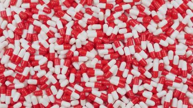 Kırmızı ve beyaz renkli sayısız kapsül bir yüzeye saçılmıştır. Sahne, kapsüllerin şekil ve renk karşıtlığını vurgulayan kaotik ama görsel açıdan ilginç bir düzenleme gösteriyor.