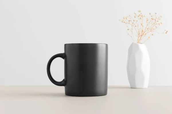 Taza Negra Maqueta Con Una Gypsophila Jarrón Sobre Una Mesa — Foto de Stock