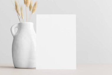 Beyaz davetiye modeli ve bej bir masada laguru. 5x7 oranı, A6, A5 'e benziyor..