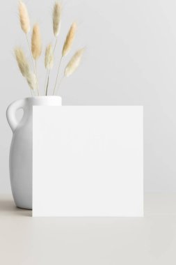 Kare davetiye modeli ve bej bir masada lagurus..