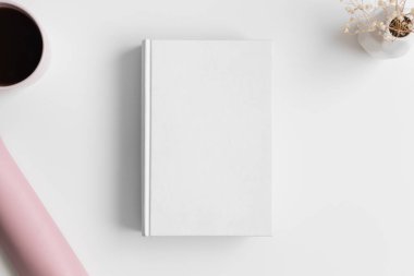 Beyaz masa üzerinde lavanta, kahve ve çalışma alanı aksesuarları olan beyaz kitap maketi..