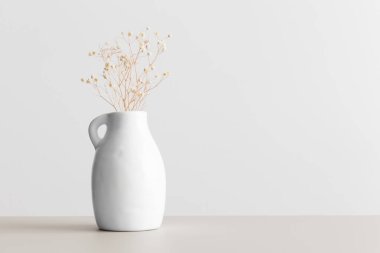 Bej bir masadaki vazoda kurutulmuş çingene. Boş kopya alanı ile düz yatıyordu.