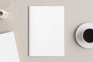 Bej masasında bir fincan kahve, kitap ve bir çigila olan dergi modeli..