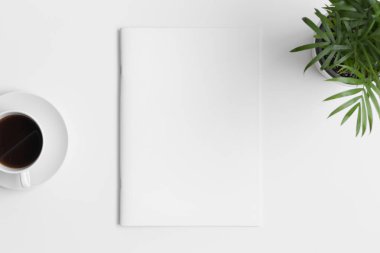 Bir fincan kahve ve beyaz masanın üzerinde bir palmiye bitkisi olan dergi modeli..