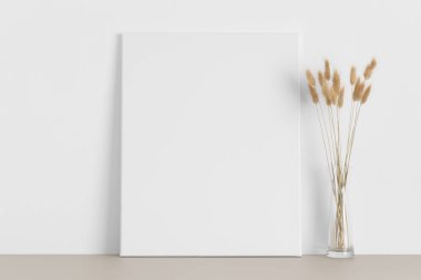 Bej masasında lagurus olan beyaz tuval..