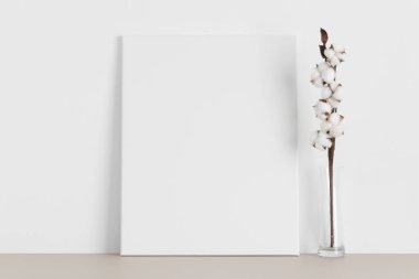 Bej masanın üzerinde pamuk dalı olan beyaz tuval..