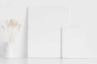 Masanın üzerinde pampa ve manikin olan iki beyaz tuval..