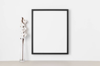 Duvarda siyah çerçeve modeli var. Pamuk dallarıyla süslenmiş..