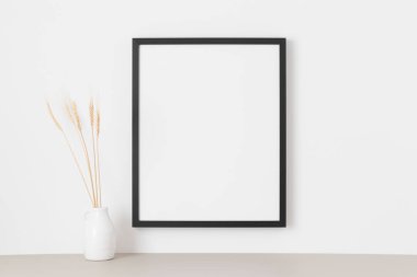 Duvarda kurumuş çiçek desenli siyah çerçeve..