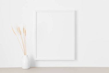 Duvarda kurumuş çiçek desenli beyaz çerçeve..