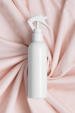 Beyaz kozmetik tetik sprey şişesi yumuşak pembe tekstil üzerinde maket..