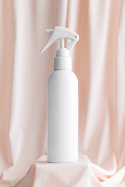 Beyaz kozmetik tetik sprey şişesi yumuşak pembe tekstil üzerinde maket..
