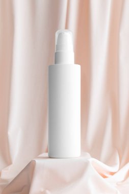 Beyaz kozmetik. Losyon şişesi yumuşak pembe tekstil üzerinde..