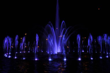 Çeşme suyu, gece mavisi ışıklarda halka halinde uçar.