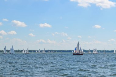 Yelkenli göl üzerinde yüzer ve mavi gökyüzü yelken açar