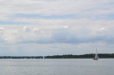 Yelkenli göl üzerinde yüzer ve mavi gökyüzü yelken açar