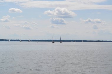 Yelkenli göl üzerinde yüzer ve mavi gökyüzü yelken açar