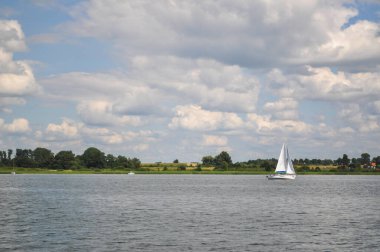 Yelkenli göl üzerinde yüzer ve mavi gökyüzü yelken açar