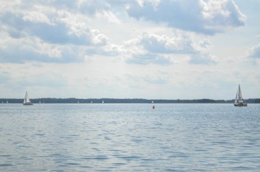 Yelkenli göl üzerinde yüzer ve mavi gökyüzü yelken açar