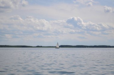 Yelkenli göl üzerinde yüzer ve mavi gökyüzü yelken açar