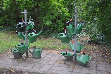 Yeşil sulama tenekeleri parktaki askıda asılı duruyor.