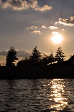 Şehir kanalında gün batımı nehir gölü ve ağaçlarda.