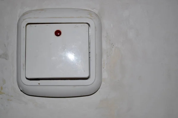 white light switch on white wall with red led dirty wall