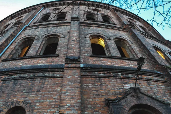 Polonya 'nın Varşova kentindeki eski doğalgaz fabrikasının etrafında birçok penceresi olan terk edilmiş tuğla bina sonbaharda dallar arasında yer alıyor.