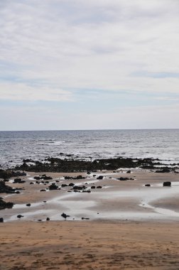 Volkanik siyah kayalar ve bulutların altında karamsar deniz