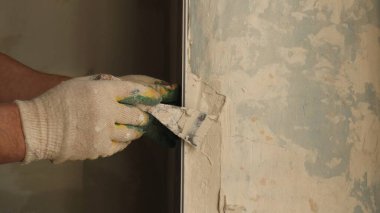 Pamuk eldivenli inşaatçının elleri dar bir spatula ile çalışır, havan tabakasını pencerenin yamacına sabitler, inşaat araçları kullanılarak iç dekorasyon sürecinde el işi