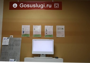 Maykop, Adygea Republic, Rusya - 20 Aralık 2020: Reklam broşürleri olan bir duvarın arka planına karşı kamu hizmetlerinin sağlandığı ofiste boş ekranlı bilgisayar