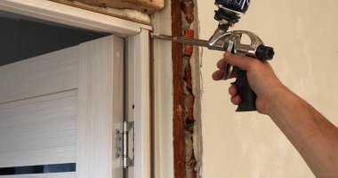 Kurucunun elinde bulunan bir inşaat silahının köpüğüyle kapı çerçevesinin hava geçirmez hale getirilmesi, büyük onarımlar sırasında iç kapıları kurma süreci