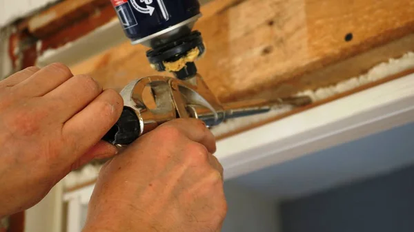 setting up the installation tool by the hands of the door installer, close-up, the hands of the worker in the process of fixing the door frame in the opening with the help of silicone foam