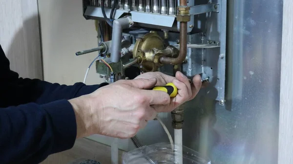 repair and adjustment of a gas boiler by hand using a screwdriver, monitoring the functioning of gas equipment, loosening screws in the structure of a home boiler, repairing a valve in a gas system