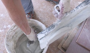 bir kovadan geniş bir spatula üzerine havan topu karışımı alır, iç dekorasyon için aletleri ve macunu olan tanınmayan bir yapıcı, bitiş sürecinin detaylarının üst görünümü