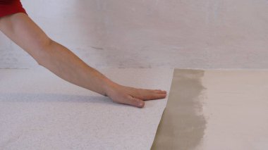 Odanın hazırlanmış duvarlarına bir parça ışık kağıdı yapıştırmak, duvar kağıdının yüzeyini elinizle pürüzsüzleştirmek, alttaki duvar kağıdı görünümünü yapıştırırken düzensizlikleri dengelemek.